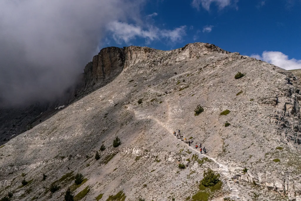Hikers walk along a narrow ridge on Mount Olympus in Greece.