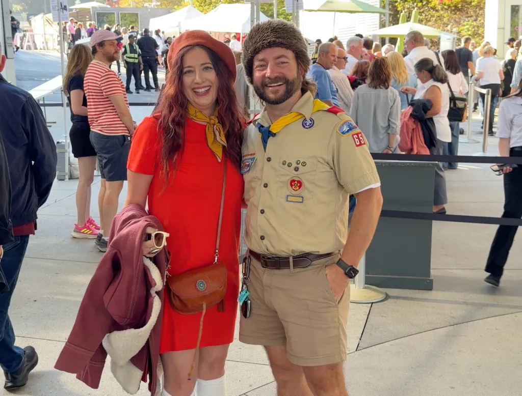 A man dressed in a Boy Scout uniform and a woman in an orange dress and beret pose at the Hollywood Bowl.