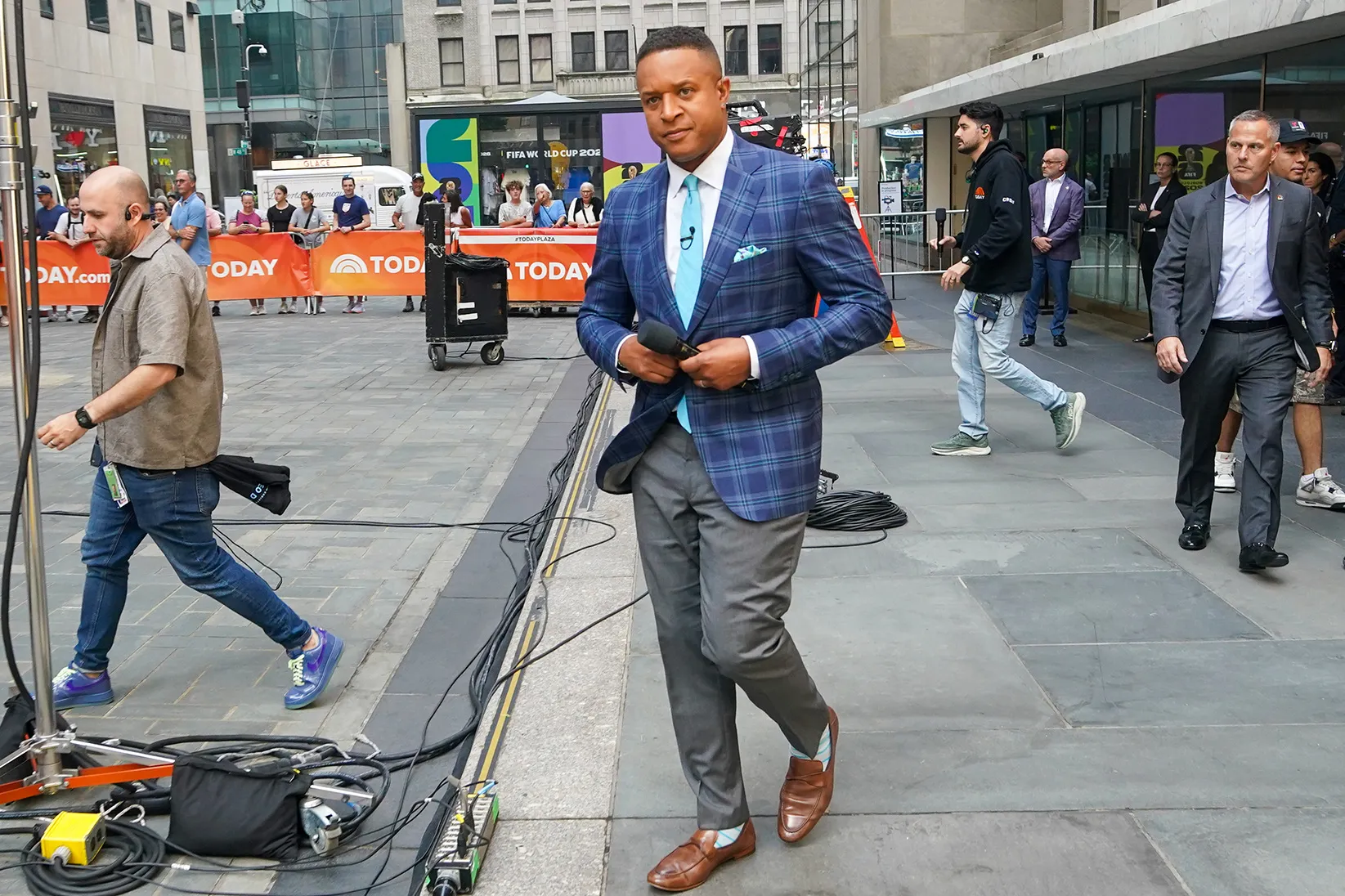 TODAY show host Craig Melvin holds a microphone while walking in Rockefeller Plaza.