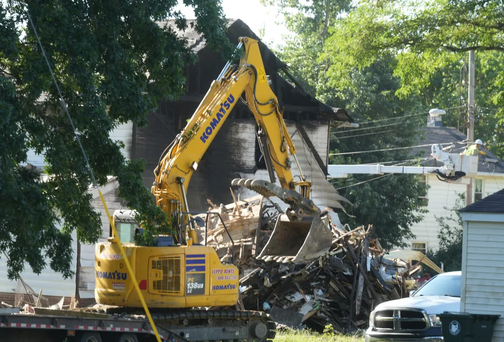 A large yellow Komatsu excavator clearing debris from an exploded house on Bonnot Place NE in Canton.