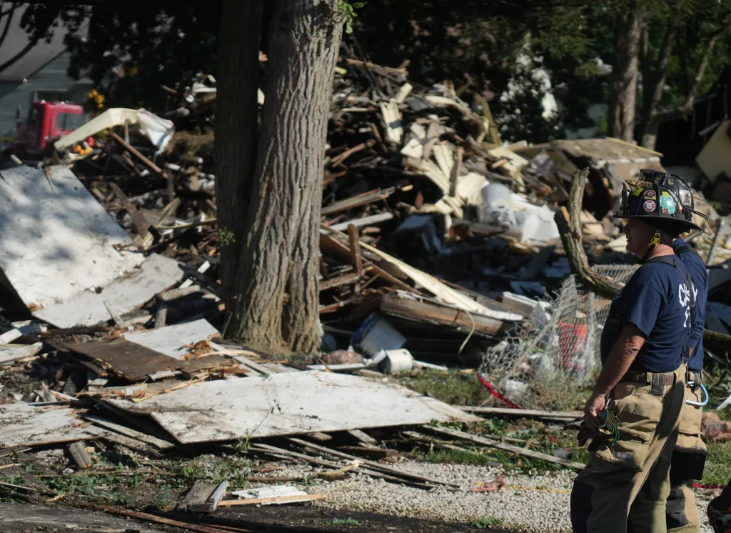 Firefighters stand in front of debris from an exploded house in Canton.
