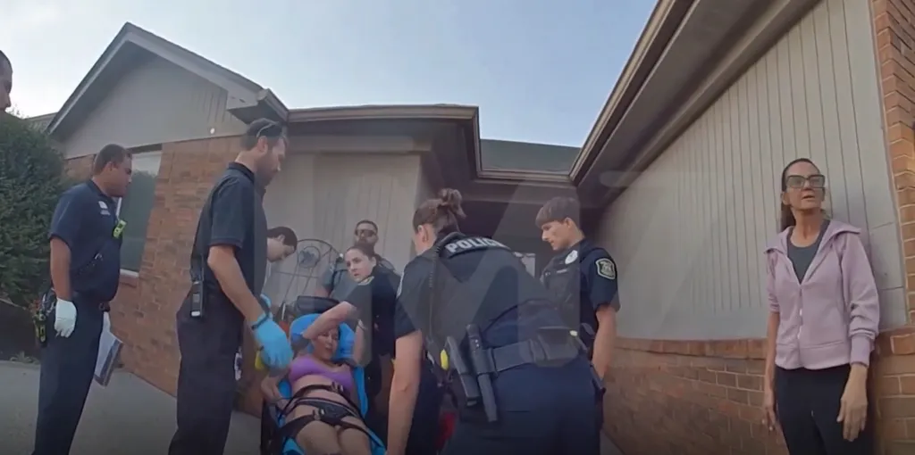 Kim Scott being loaded onto a stretcher by emergency personnel and police.