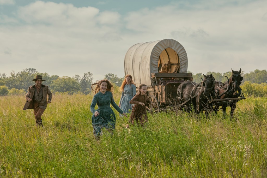Luke Bracey, Skywalker Hughes, Crosby Fitzgerald, and Alice Halsey running in a field next to a covered wagon pulled by horses, from "Little House on the Prairie."