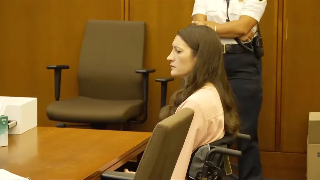 Lindsay Clancy in a wheelchair, looking distressed, with a prosecutor behind her.