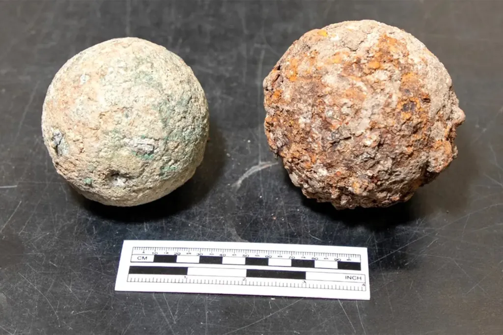 A bronze cannonball and an iron cannonball next to a ruler for scale.