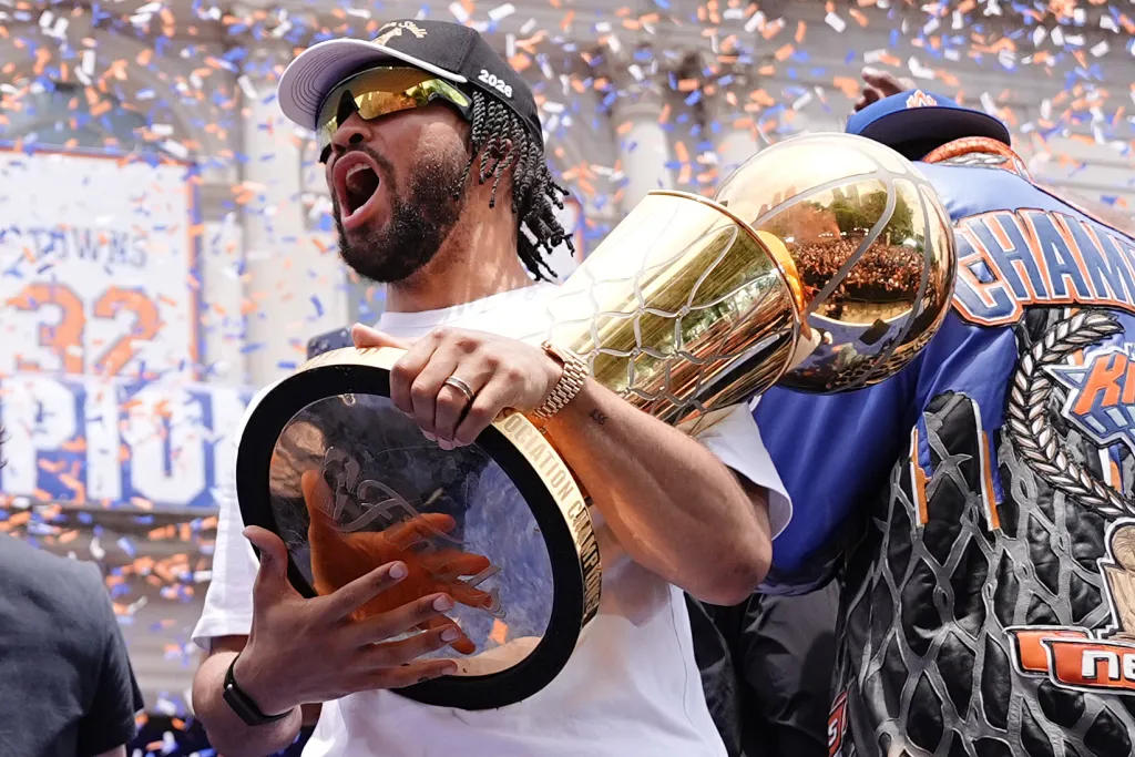Jalen Brunson celebrates with the Larry O'Brien Championship Trophy at the New York Knicks Championship parade.