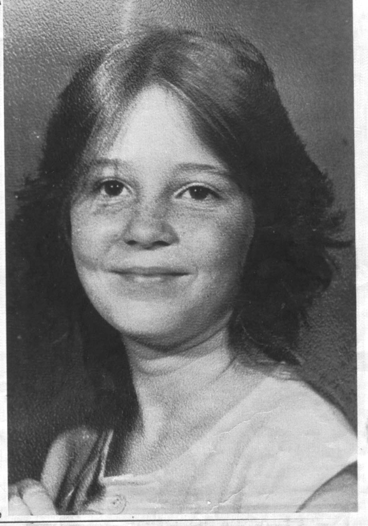 Black and white photo of Teresa Mae McAbee, an 11-year-old girl with dark hair and freckles, smiling faintly.