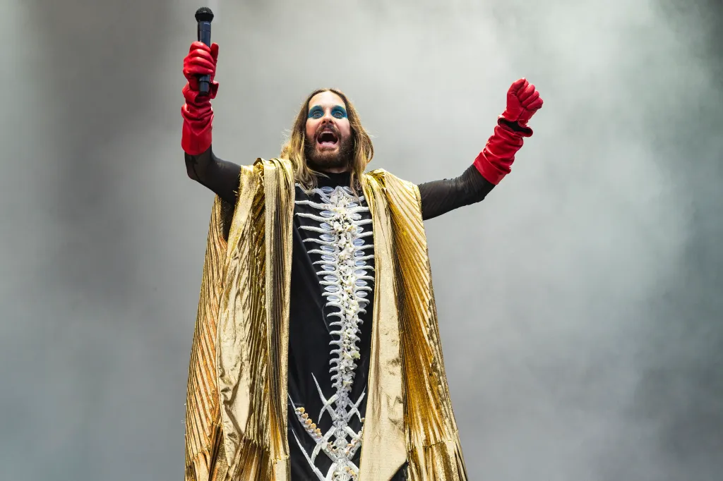 Jared Leto of Thirty Seconds to Mars performs in a skeleton costume and gold cape, holding a microphone.