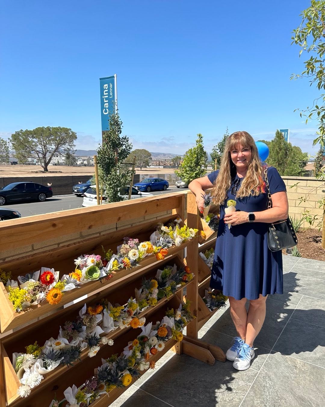 Jeana Keough standing next to a flower display with a banner for "Carina Lennar" in the background.