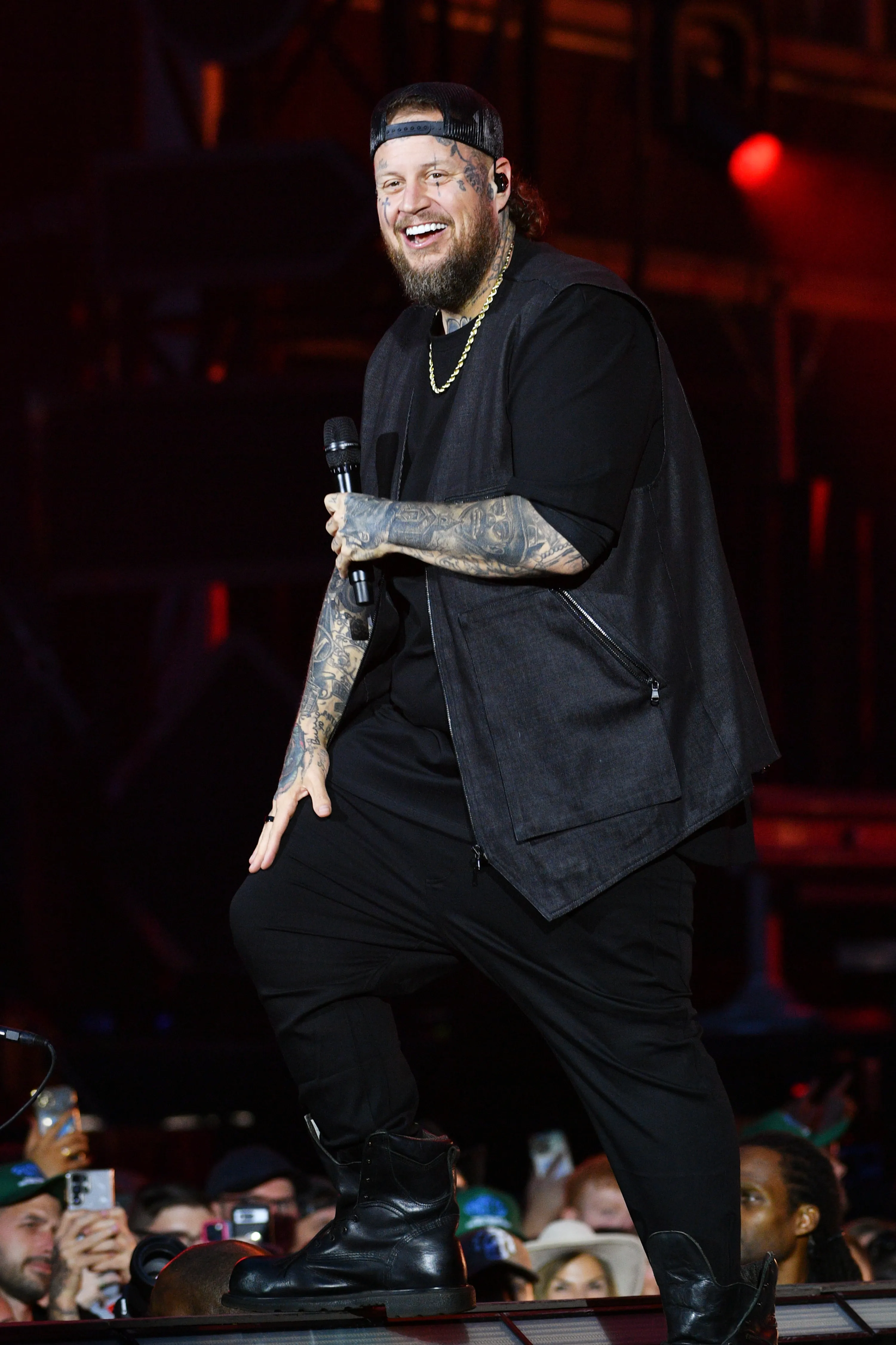 Jelly Roll performing on stage, wearing a black outfit and holding a microphone.