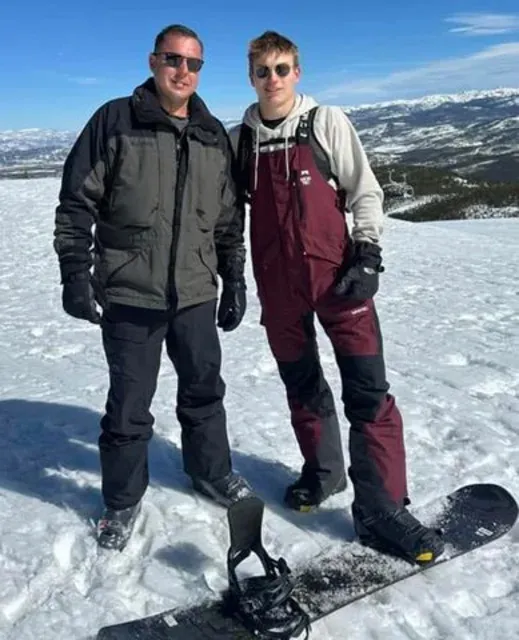 Jimmy Don Lewis and his son, Brayden Ty Lewis, on a snowy mountain with a snowboard.