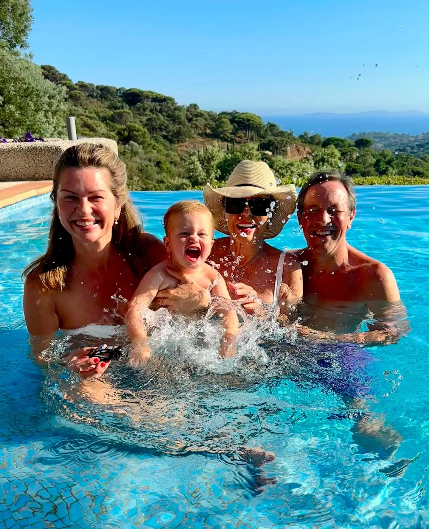 Joan Collins, Alison Papworth, a baby, and another person in a swimming pool.
