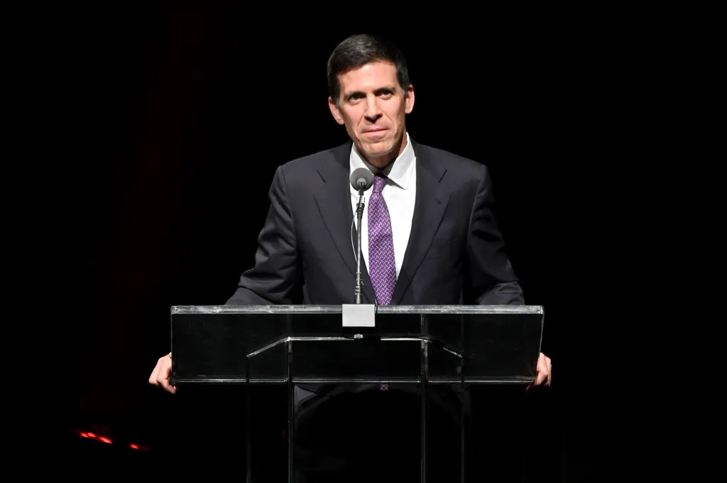 John E. Waldron speaking at a podium.