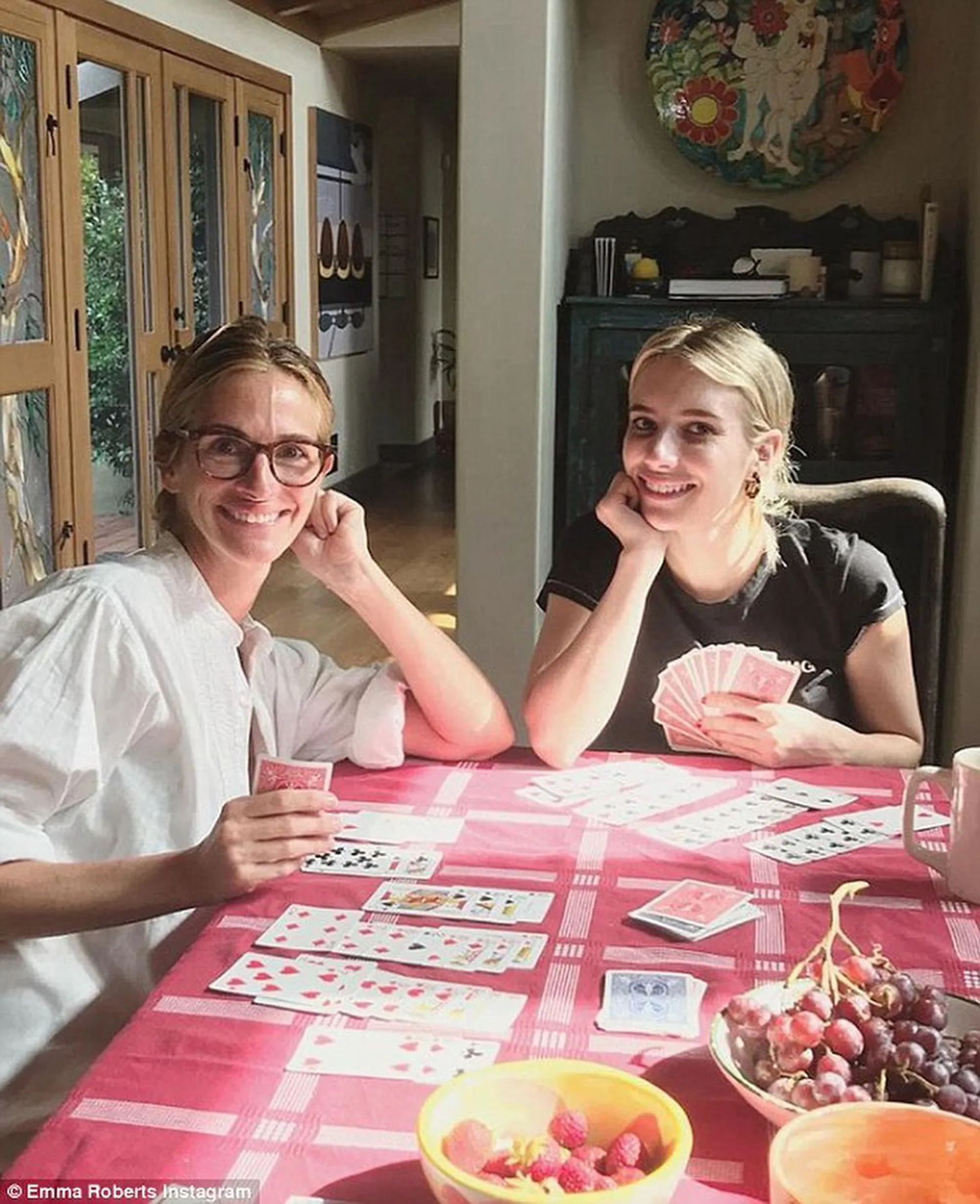 Julia Roberts and Emma Roberts playing cards at a table.