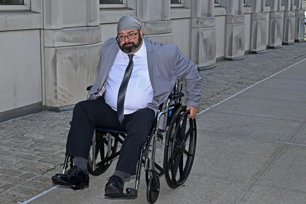 John Merrone in a wheelchair outside Brooklyn Federal Court.
