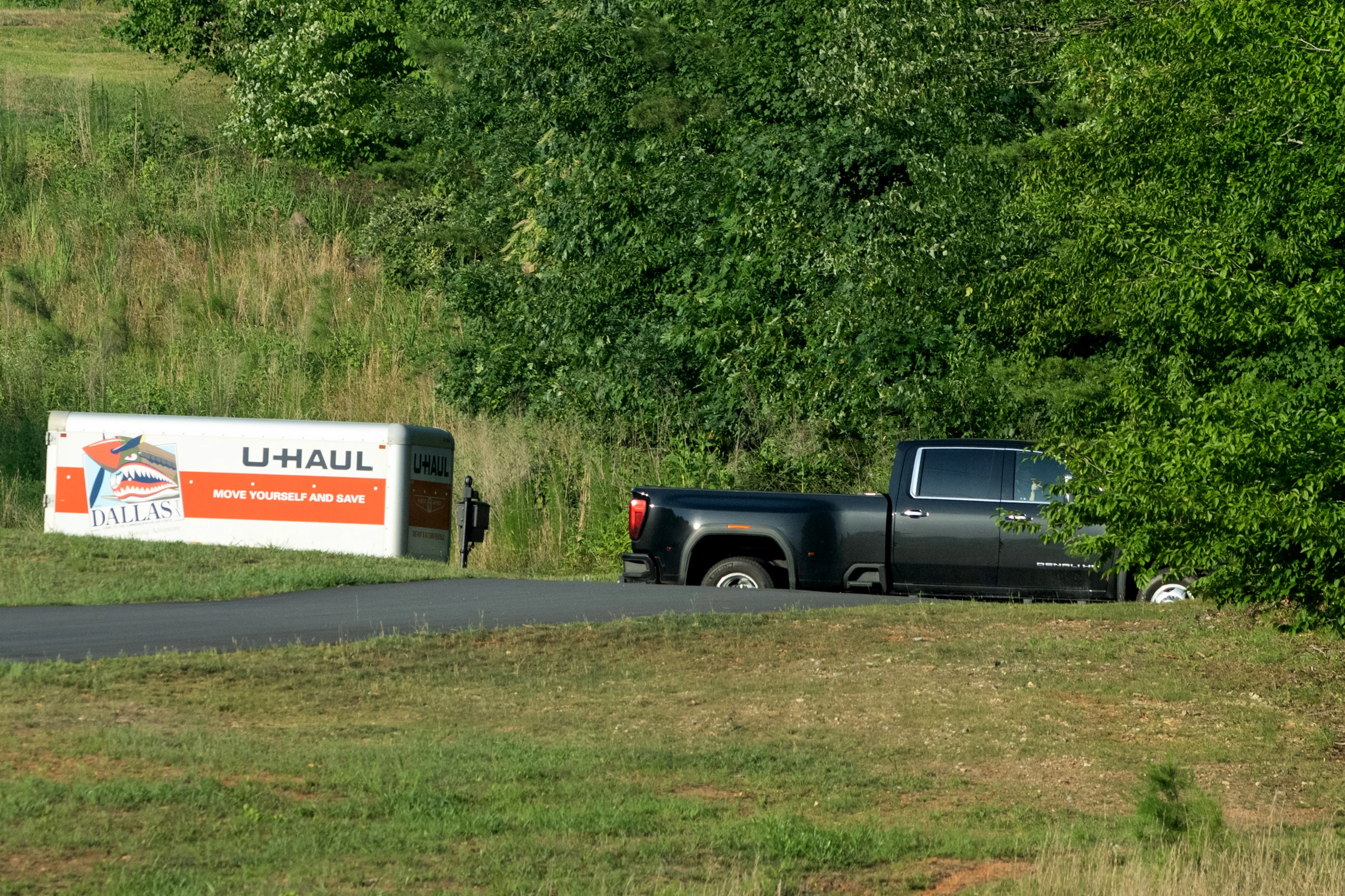 A black GMC Denali pickup truck with a U-Haul trailer attached.