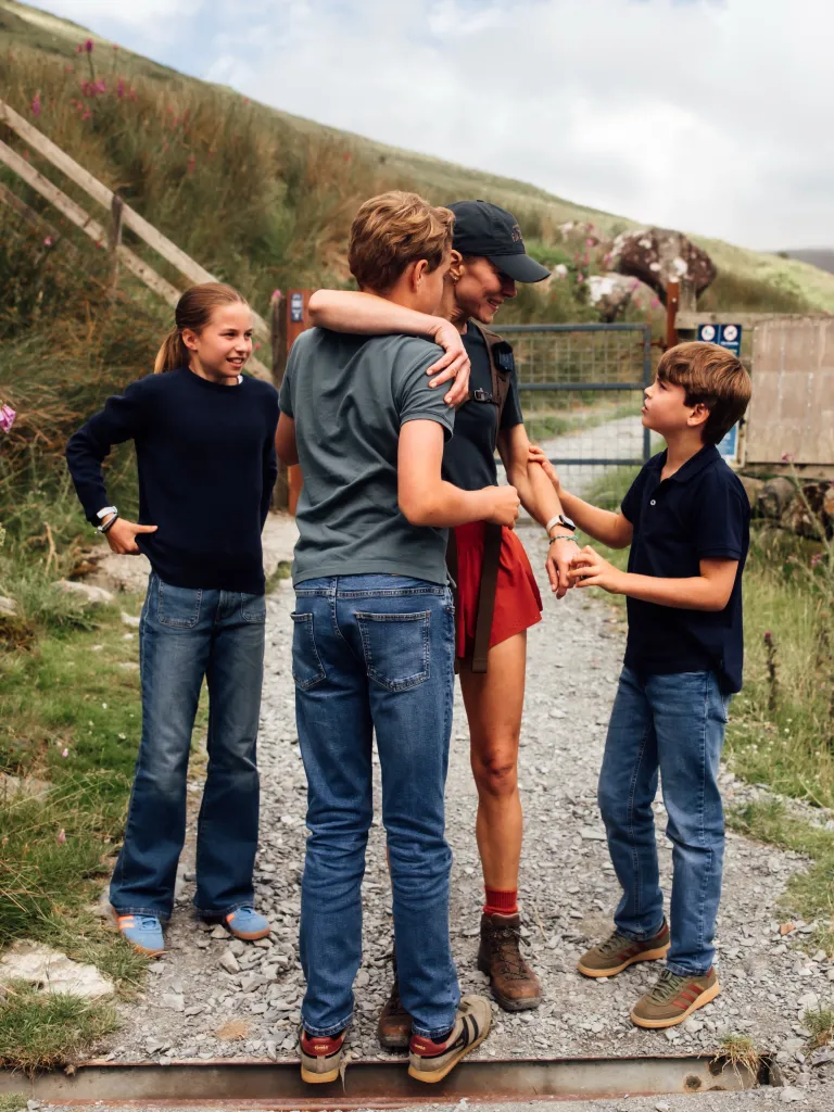 Kate Middleton standing with her three children, Prince George, Princess Charlotte, and Prince Louis, in a natural outdoor setting.