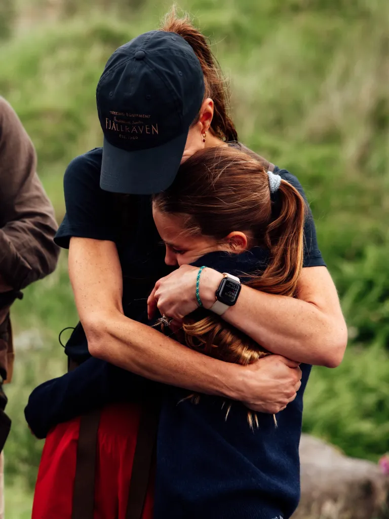 A woman in a baseball cap embraces a child.