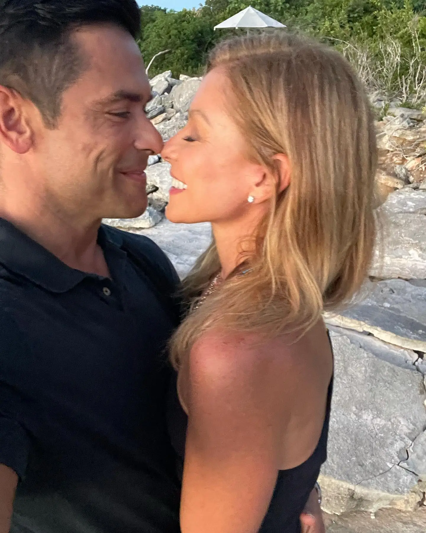 Kelly Ripa and Mark Consuelos almost touching noses and smiling at each other.