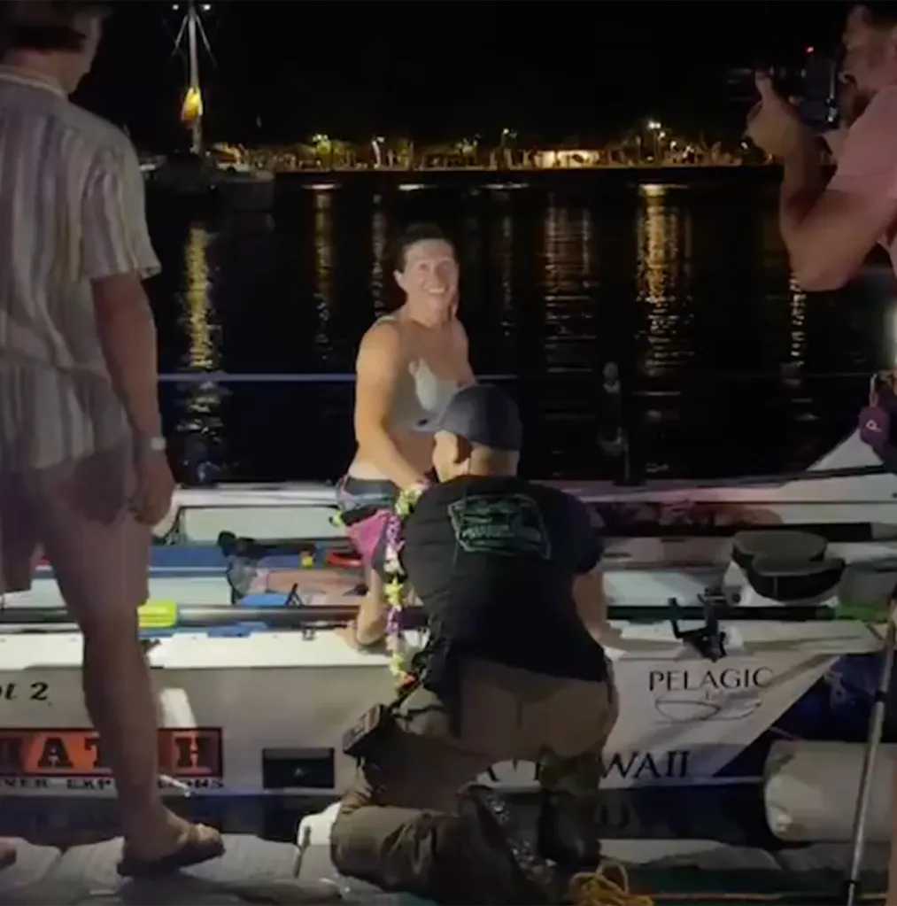 Kelsey Pfendler celebrates on her boat after completing her solo rowing trip.