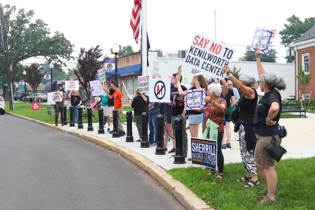 A group of people protesting a proposed data center in Kenilworth, New Jersey, holding signs that read "SAY NO TO KENILWORTH DATA CENTER" and "NO DATA CENTER."