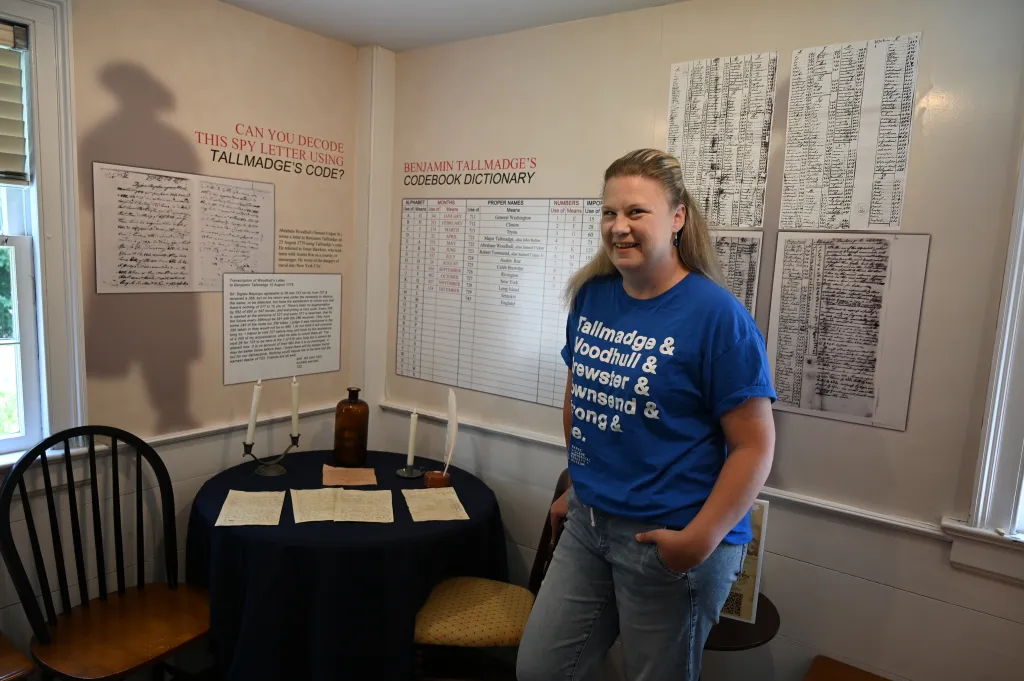 Kimberly Phyfe, an expert on the Culper Spy Ring, stands next to a display of spy letters and a codebook dictionary from the American Revolution.