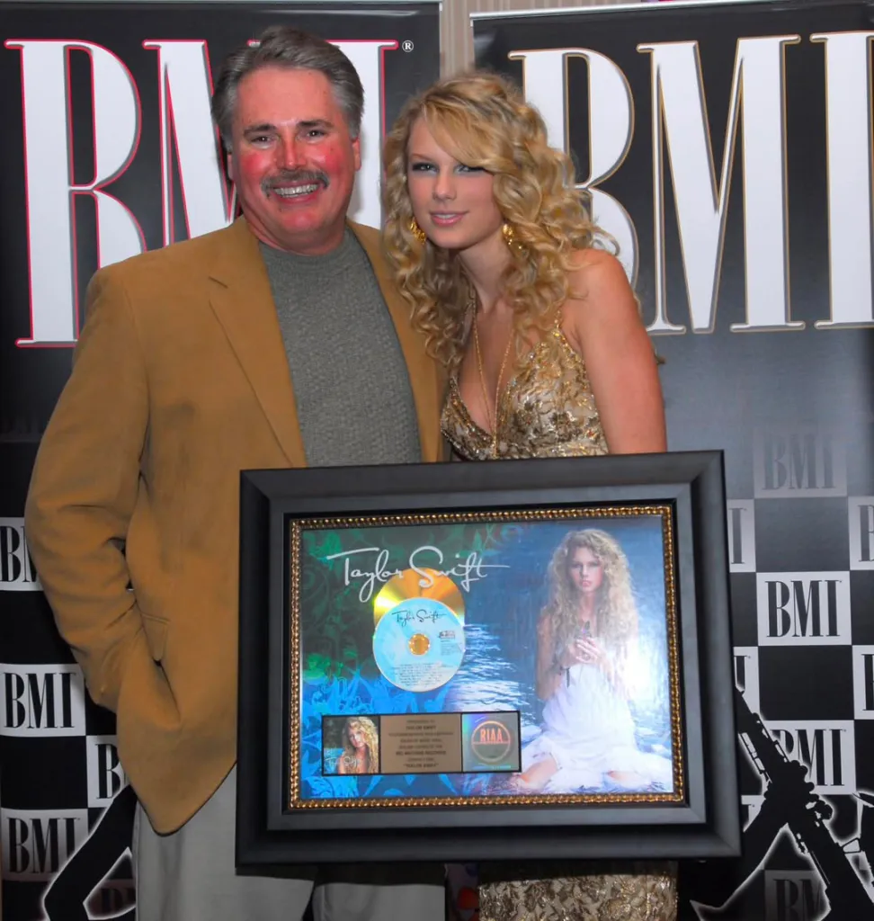 Kirk Schwabe, Taylor Swift's former teacher and bodyguard, and Taylor Swift pose with an award.