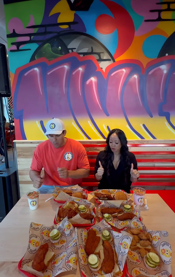 Kris Humphries and a woman sitting at a table filled with chicken dishes.
