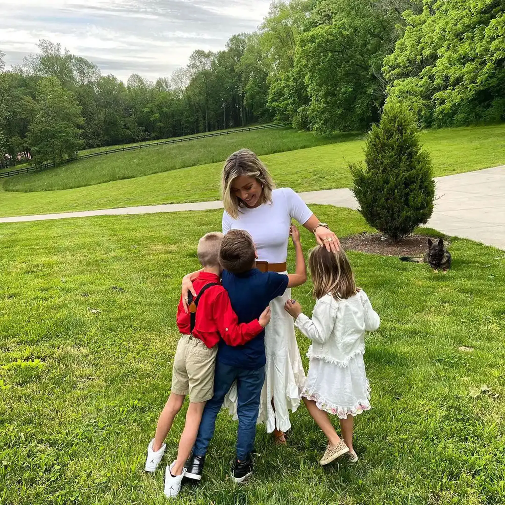Kristin Cavallari smiling while embracing her three children in a grassy field.