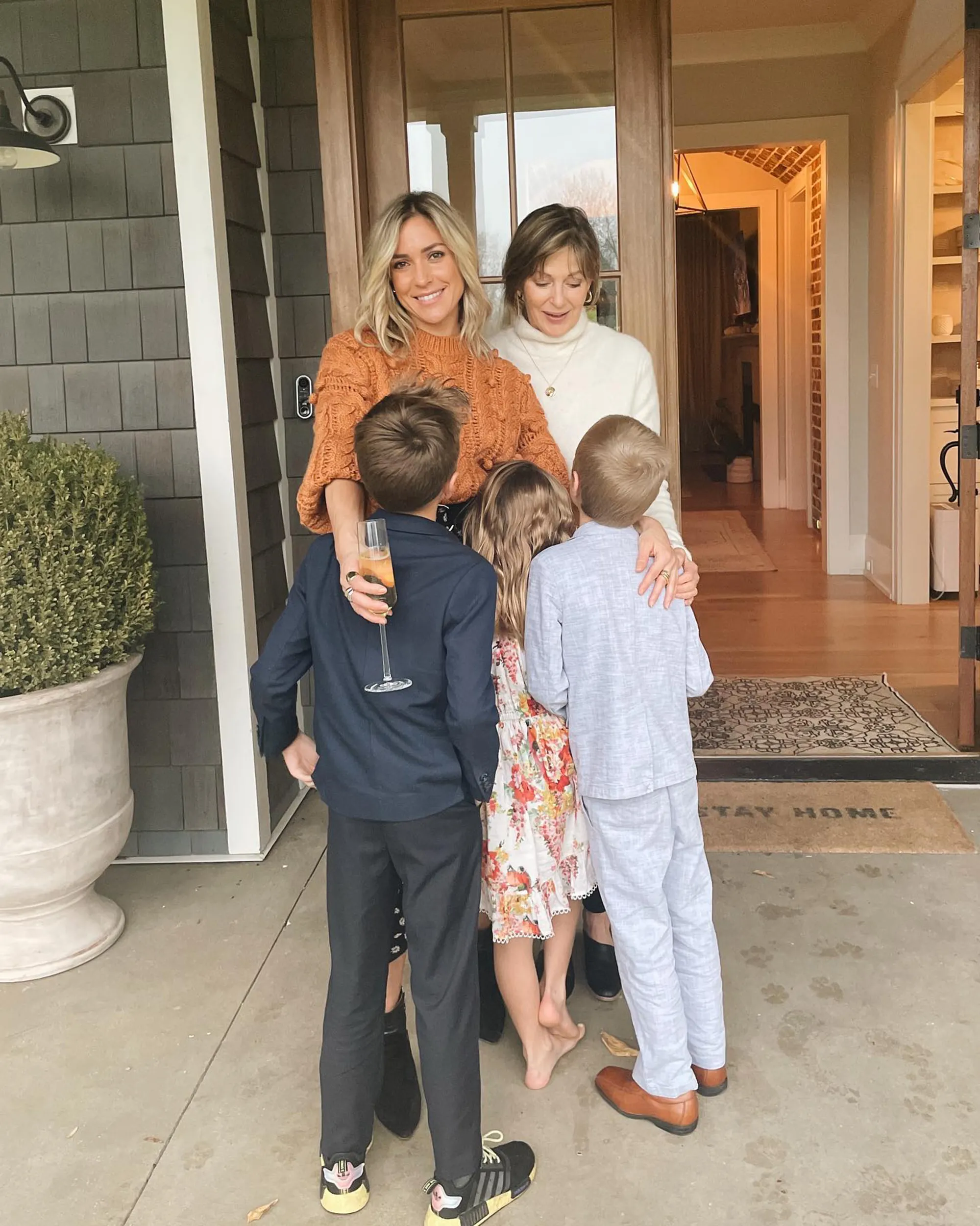Kristin Cavallari and another woman embrace three children outside a home.