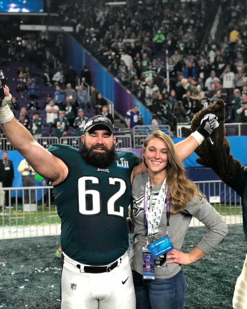 Jason Kelce in an Eagles jersey and Kylie Kelce smiling on a football field.