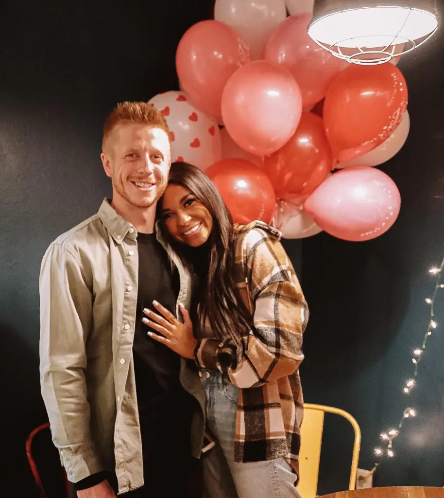 Layla Taylor and Clayton Wessel posing in front of pink and red balloons.