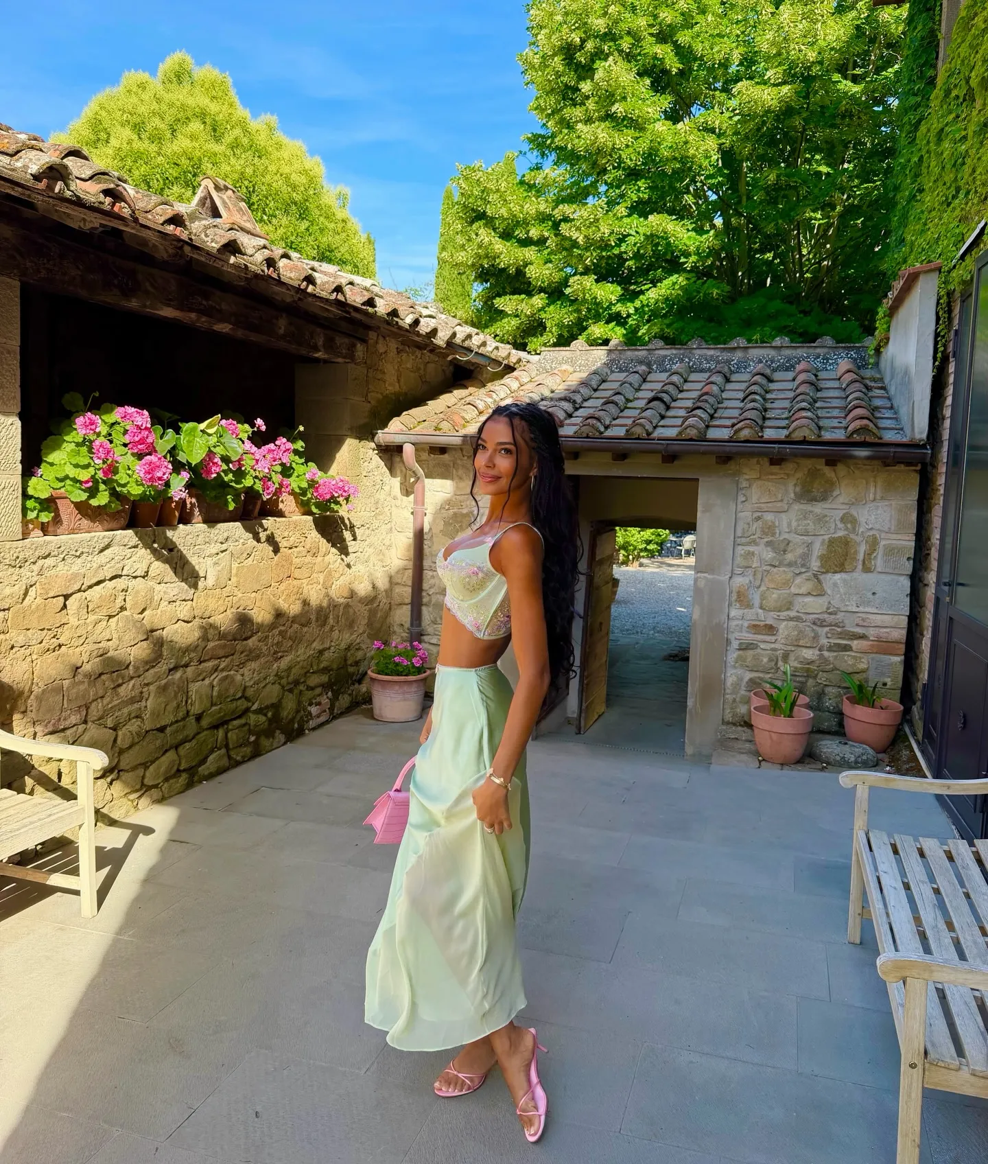Layla Taylor in a light green two-piece outfit and pink accessories, posing outdoors.
