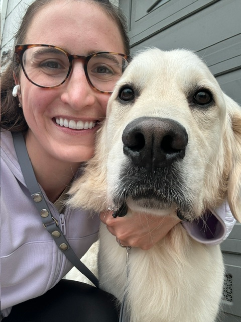 Lea Marie smiling and holding her golden retriever.