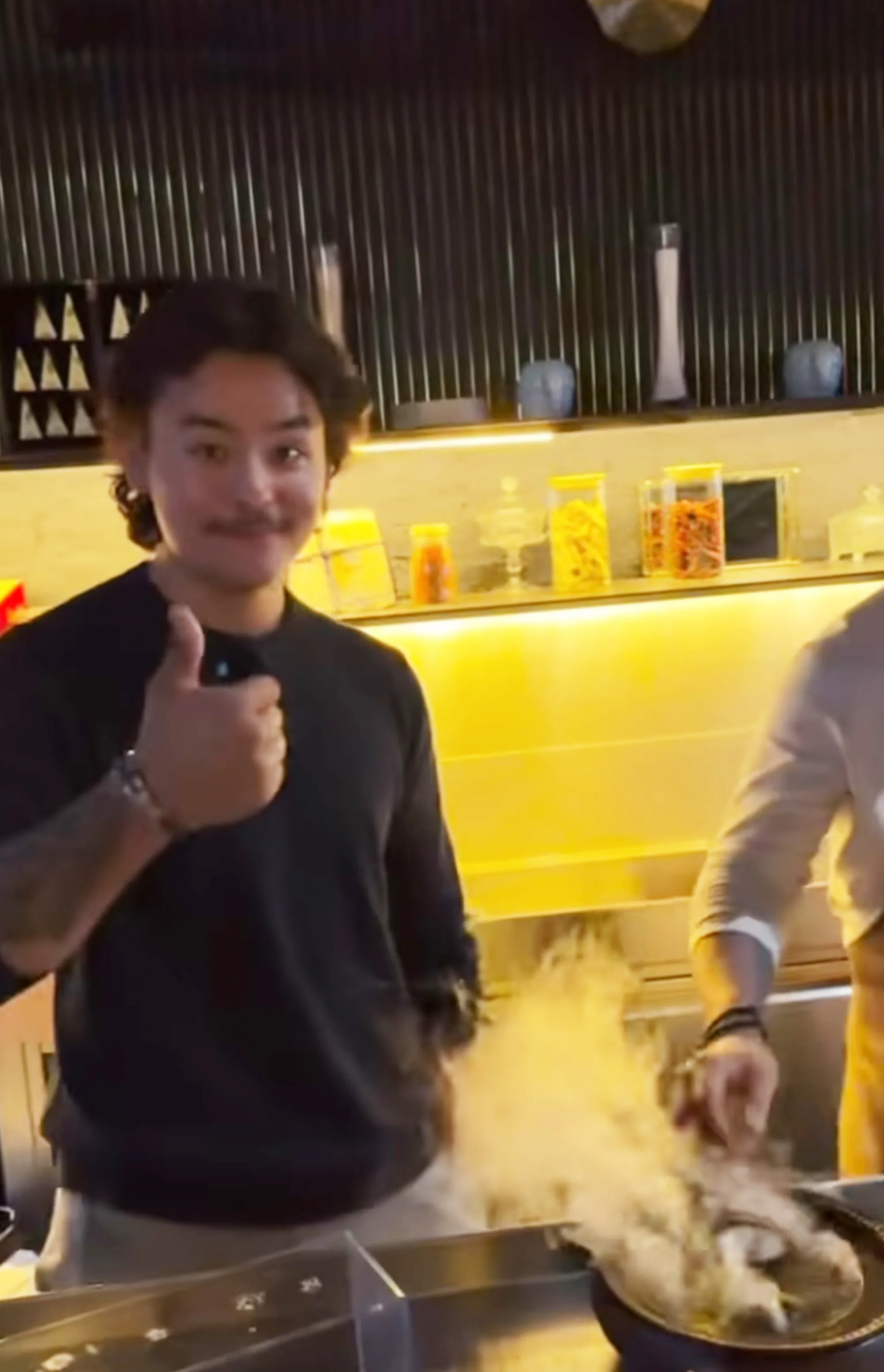 Collin Gosselin gives a thumbs-up gesture while standing over a steaming dish.
