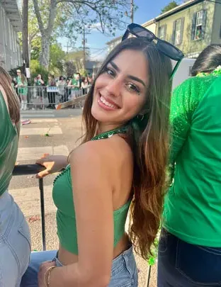 Lilly Dalton smiling, wearing a green top with sunglasses on her head.
