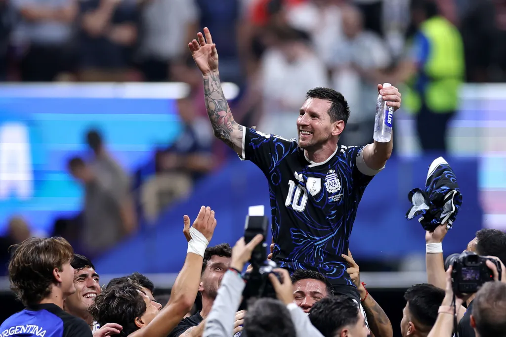 Lionel Messi #10 of Argentina is lifted by teammates, celebrating a 2-1 win.