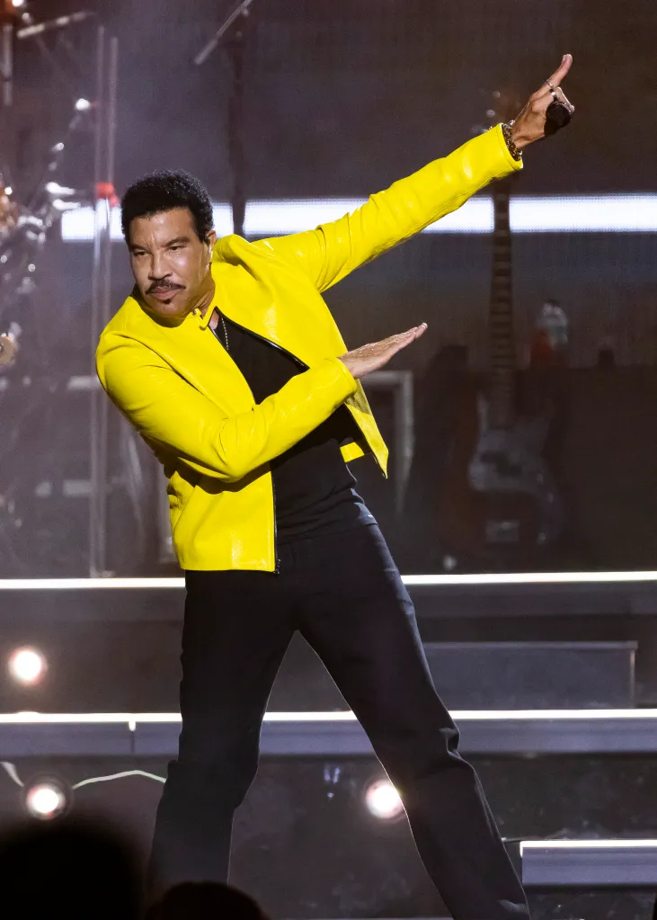 Lionel Richie in a yellow jacket performing on stage.