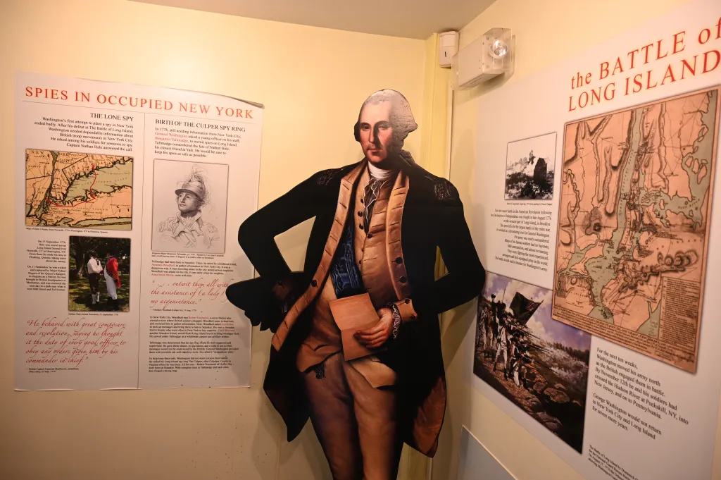 An exhibition wall with text and images about the Culper Spy Ring, featuring a cutout of George Washington.