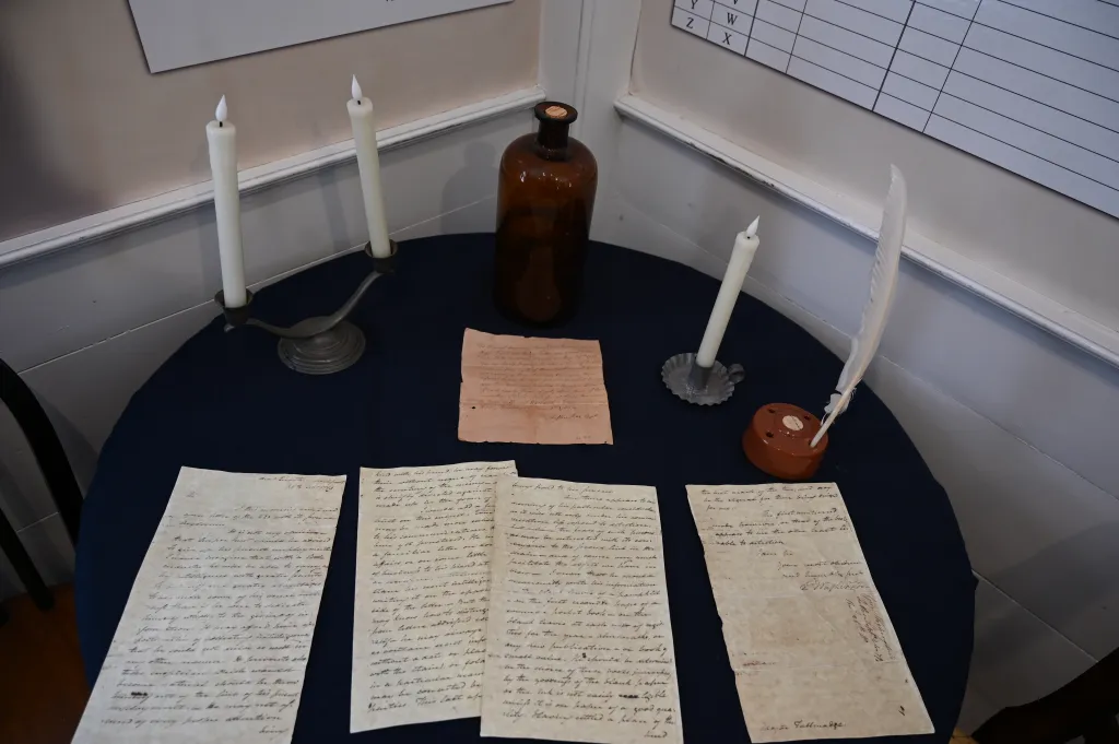 Memorabilia from the Culper Spy Ring, with letters, candles, and an inkwell.