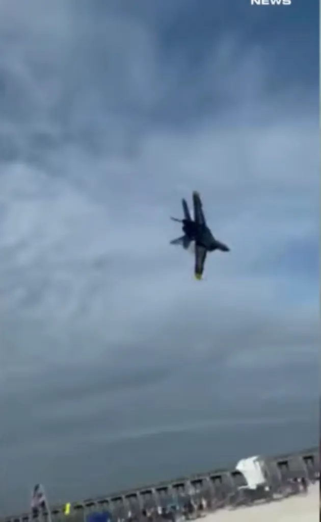 A jet aircraft flying upside down over a beach.