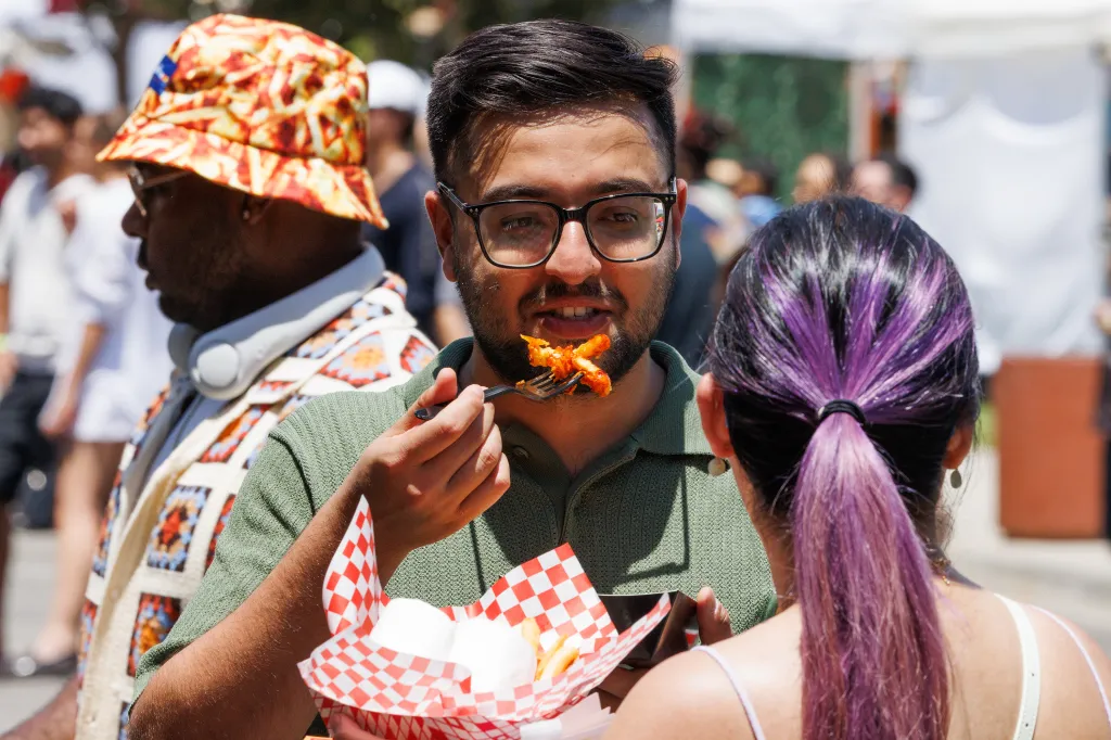 Man wearing glasses eating French fries from a paper tray.