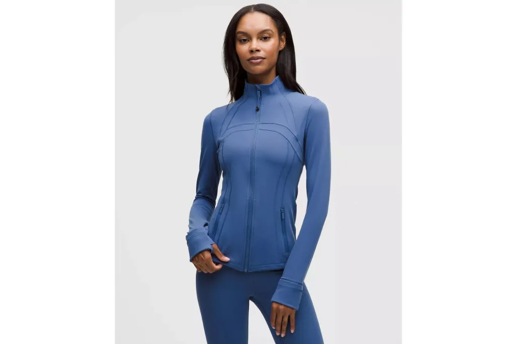 A woman in a blue running jacket and blue leggings.