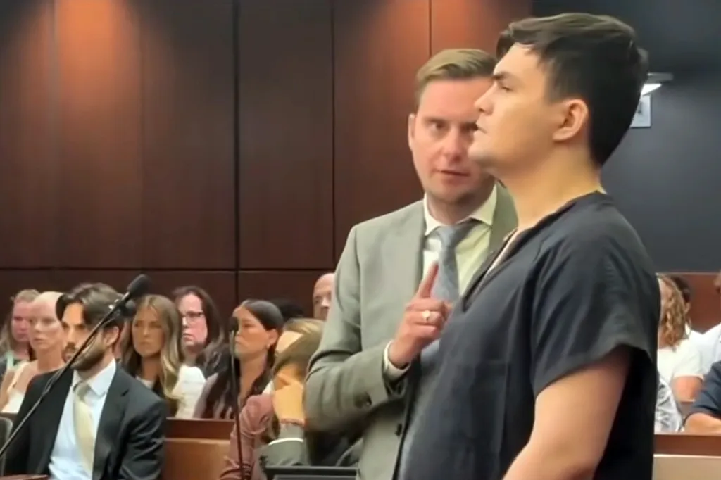 Endi Bala in a black shirt, standing next to his lawyer in a light suit, in a courtroom.