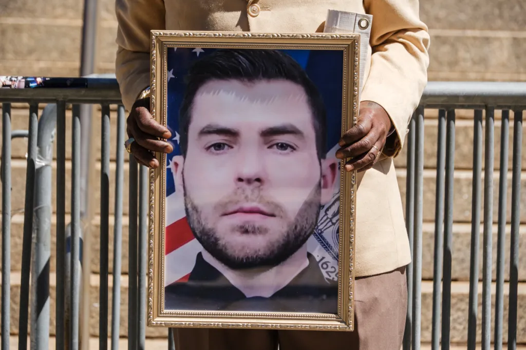 A man holds a framed photo of Jonathan Diller.