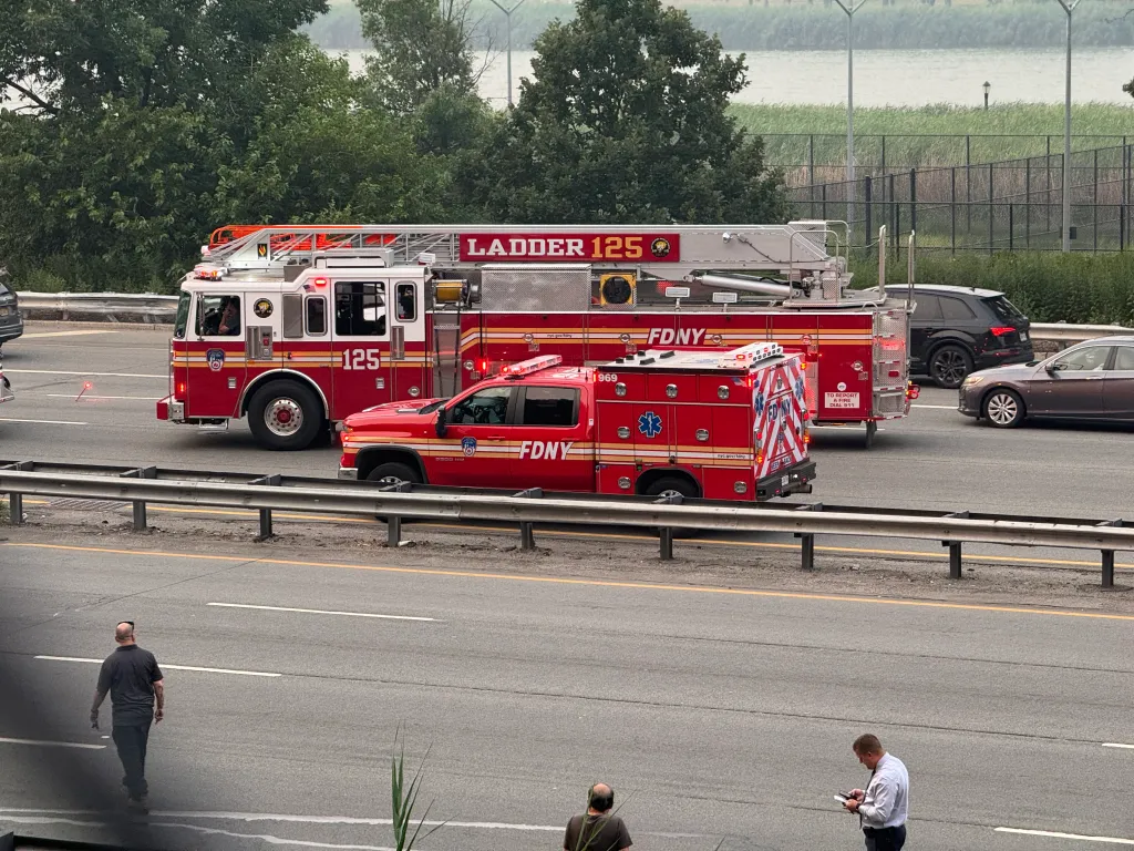 FDNY Ladder 125 fire truck and a red FDNY ambulance on a highway after a crash.