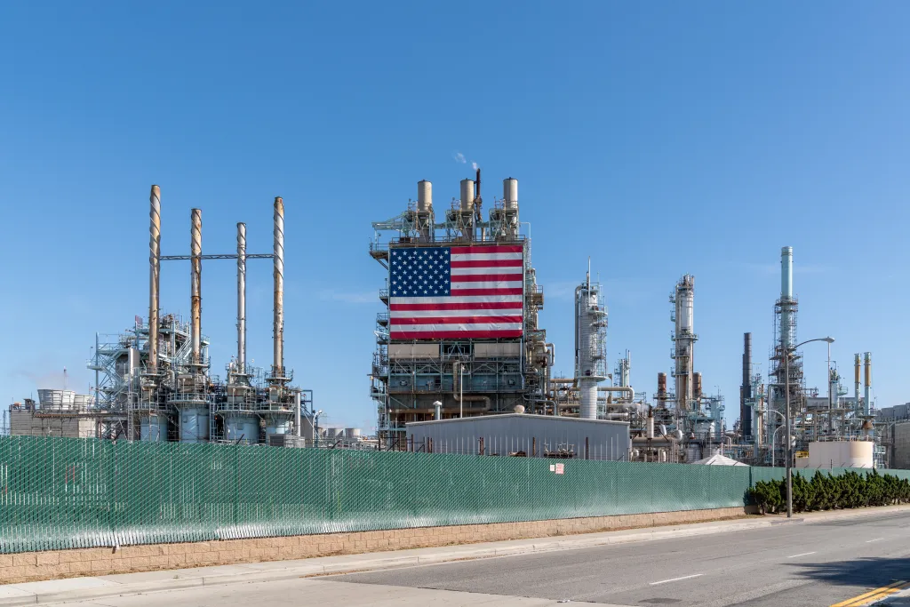 The Marathon Petroleum Los Angeles Refinery, with a large American flag hanging on one of its structures, as seen from the street.