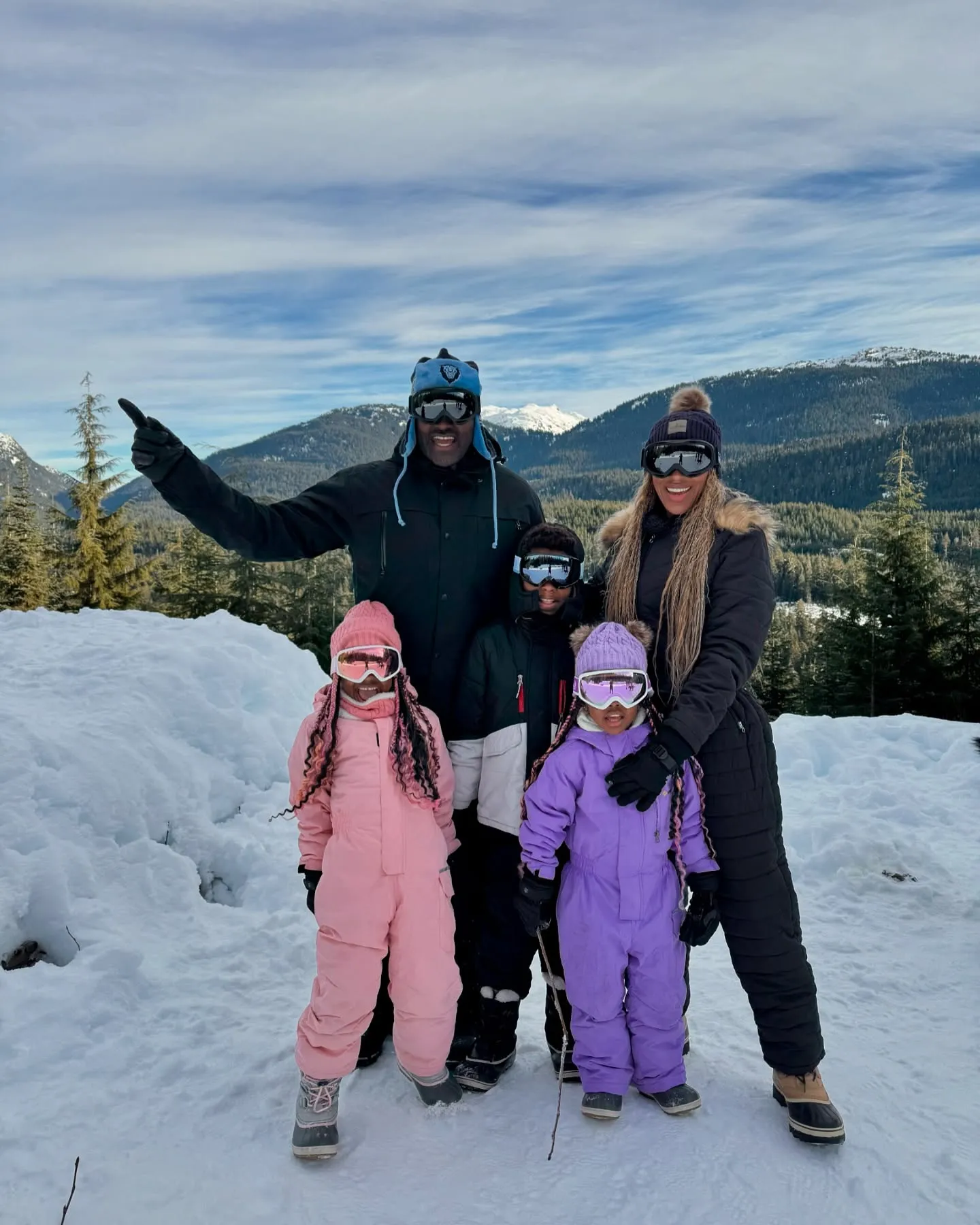 Marcellus Wiley, Annemarie Wiley, and their two children posing in snow gear on a snowy mountain.