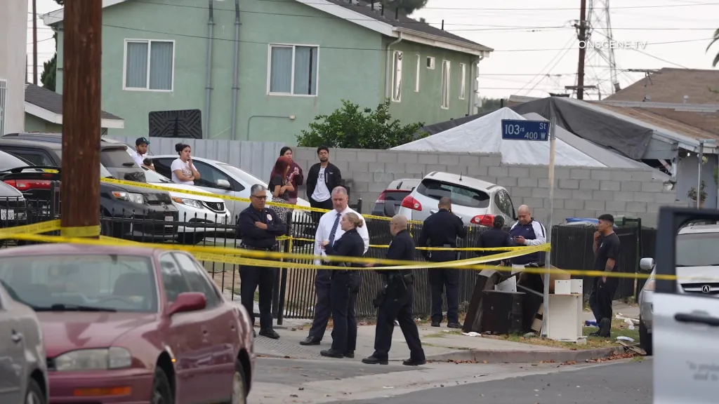 Police and bystanders behind yellow tape at a crime scene on the 400 block of West 103rd Street.