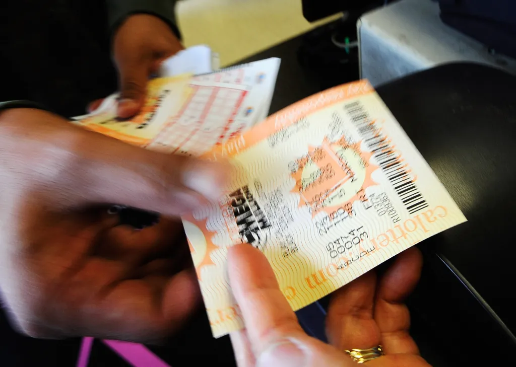 A close-up of a Mega Millions lottery ticket being held by two hands.